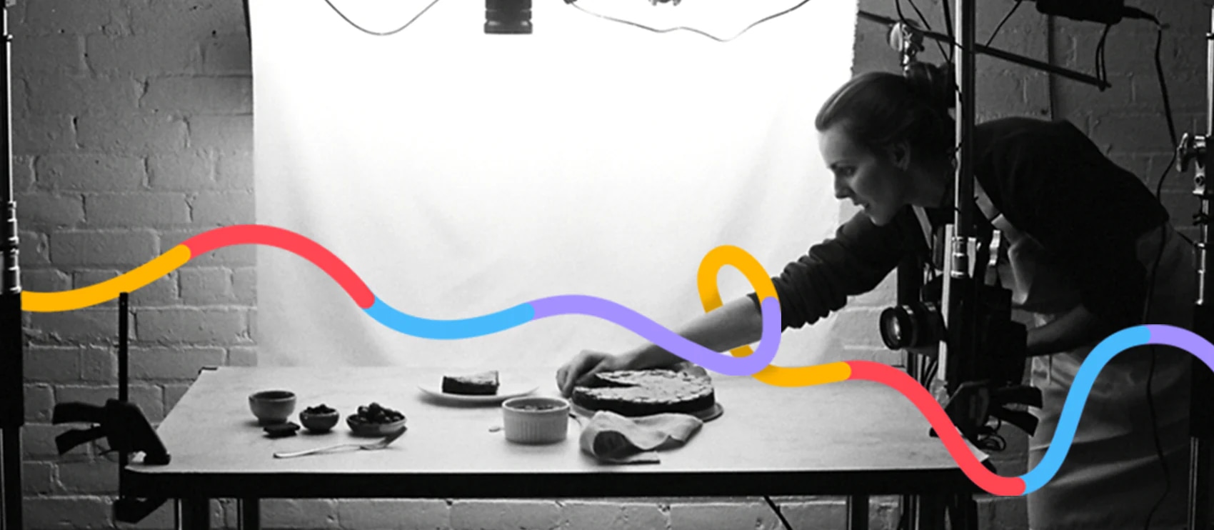 Photographer arranging a food setup in a studio with lighting and background for product photography.