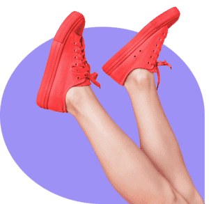 Red sneakers worn on crossed legs against a purple background, highlighting clipping path editing for a clean and vibrant finish.