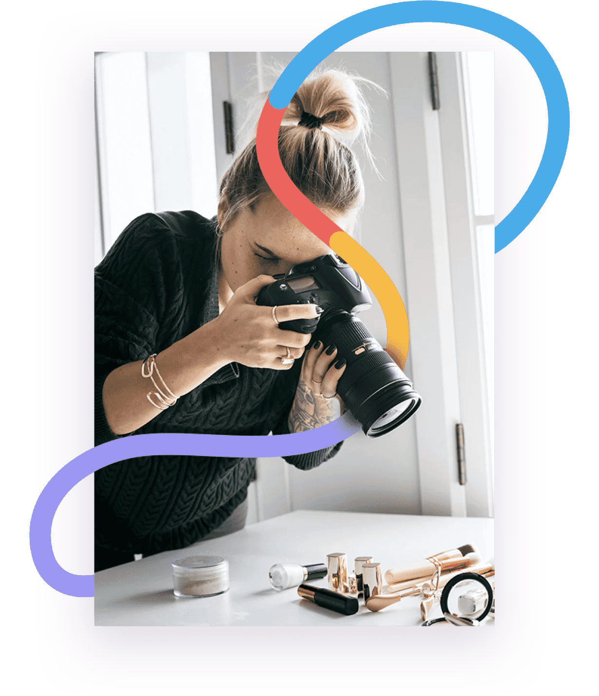A photographer capturing makeup products on a white table, showcasing a professional photo editing studio environment.